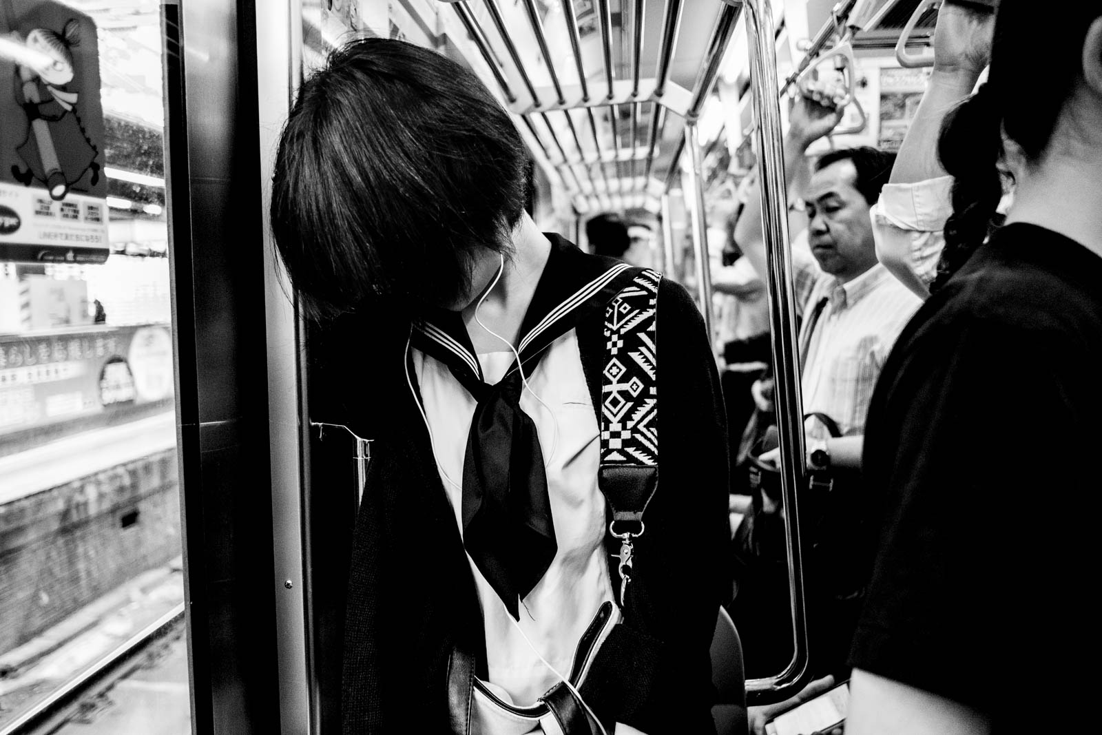 Japanese girl in metro with hair in front of her face totally secluded from her surroundings. Street photography by Victor Borst