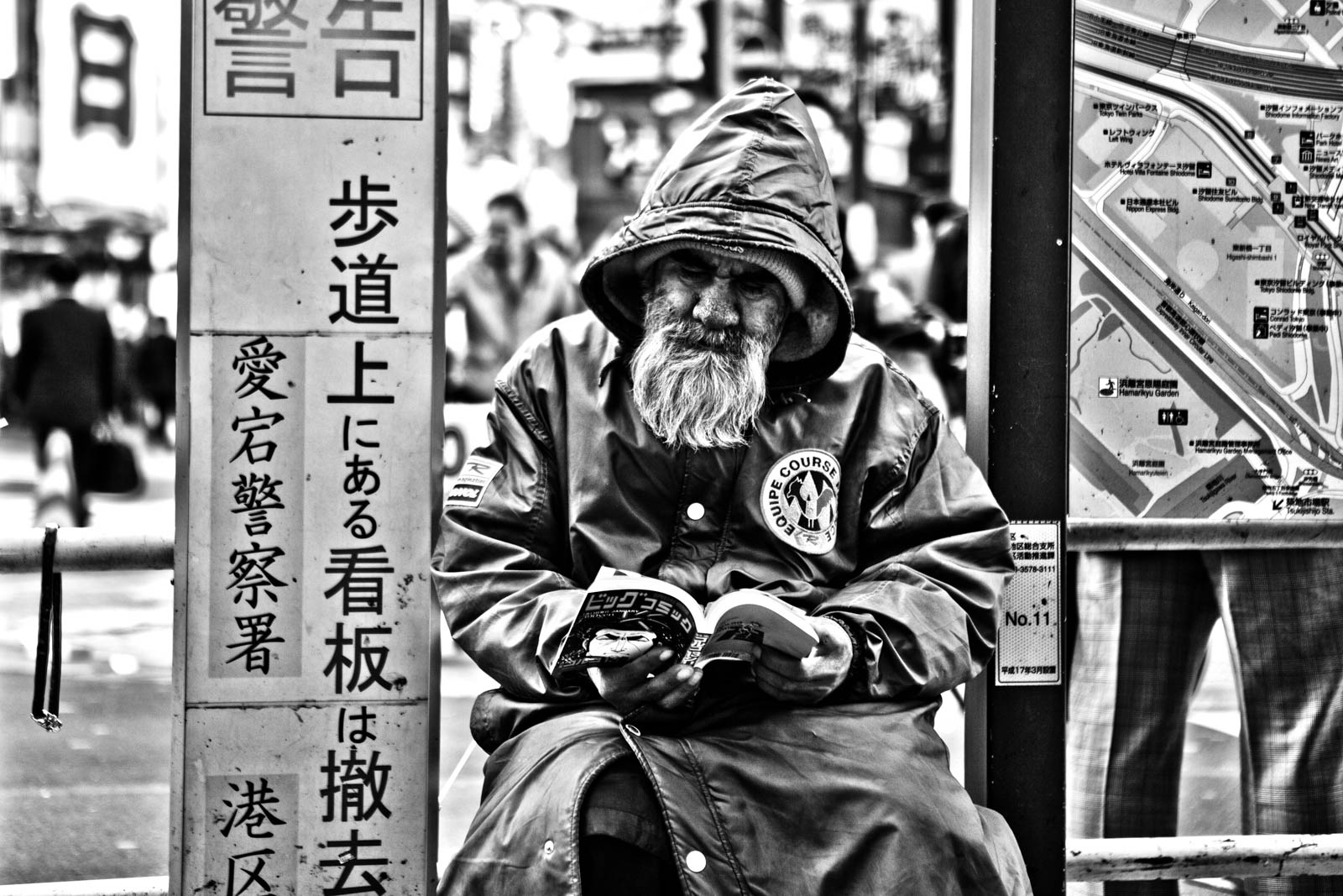 Japanese Homeless at Shimbashi station reading a manga in winter. Street Photography by Victor Borst
