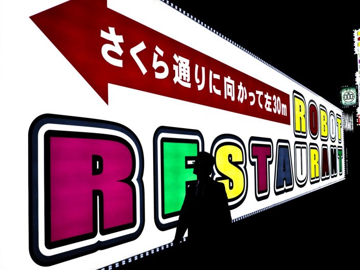 Robot Restaurant sign in Shinjuku, Tokyo. A man is walking in front of the sign.