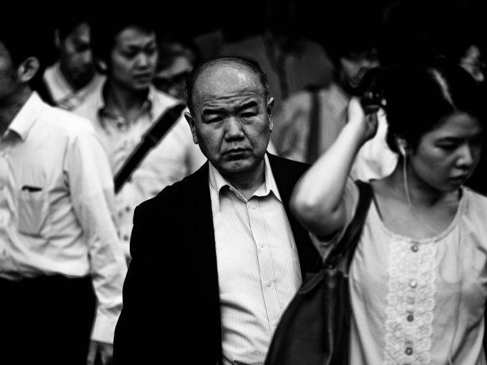 A portrait in the crowd during rush hour in the morning at Shimbashi station. Street Photography by Victor Borst