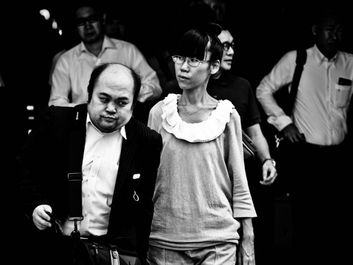 One semi-bald man and one woman with glasses going to work at Shimbashi station. Street Photography by Victor Borst