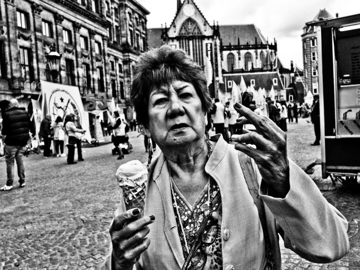 An older lady flipping the finger on the Dam Square in Amsterdam. Street Photography by Victor Borst.