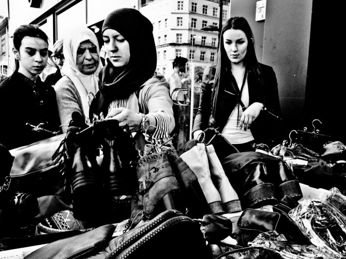 Four ladies doing some shoe shopping hunting for a bargain. Street photography by Victor Borst.