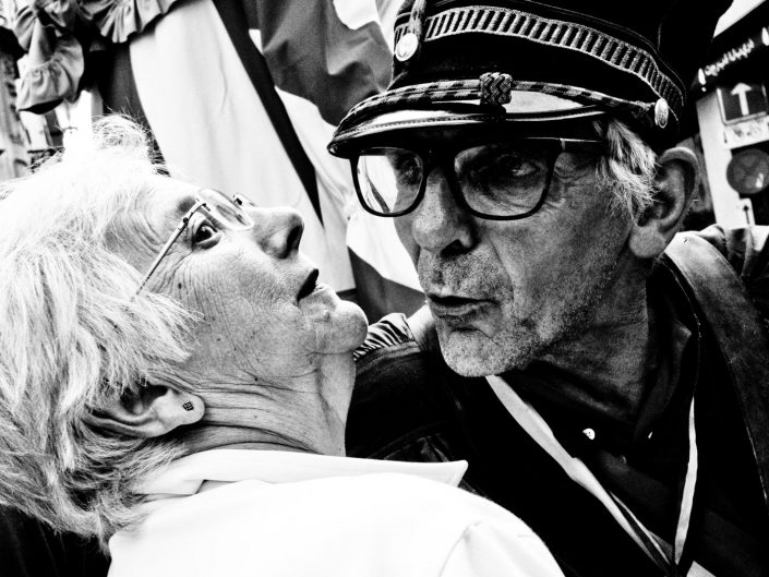 An old man trying to kiss an old lady. She looks scared. Street Photography by Victor Borst
